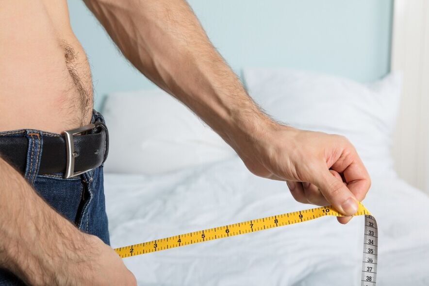 A young man takes measurements of the length of his penis
